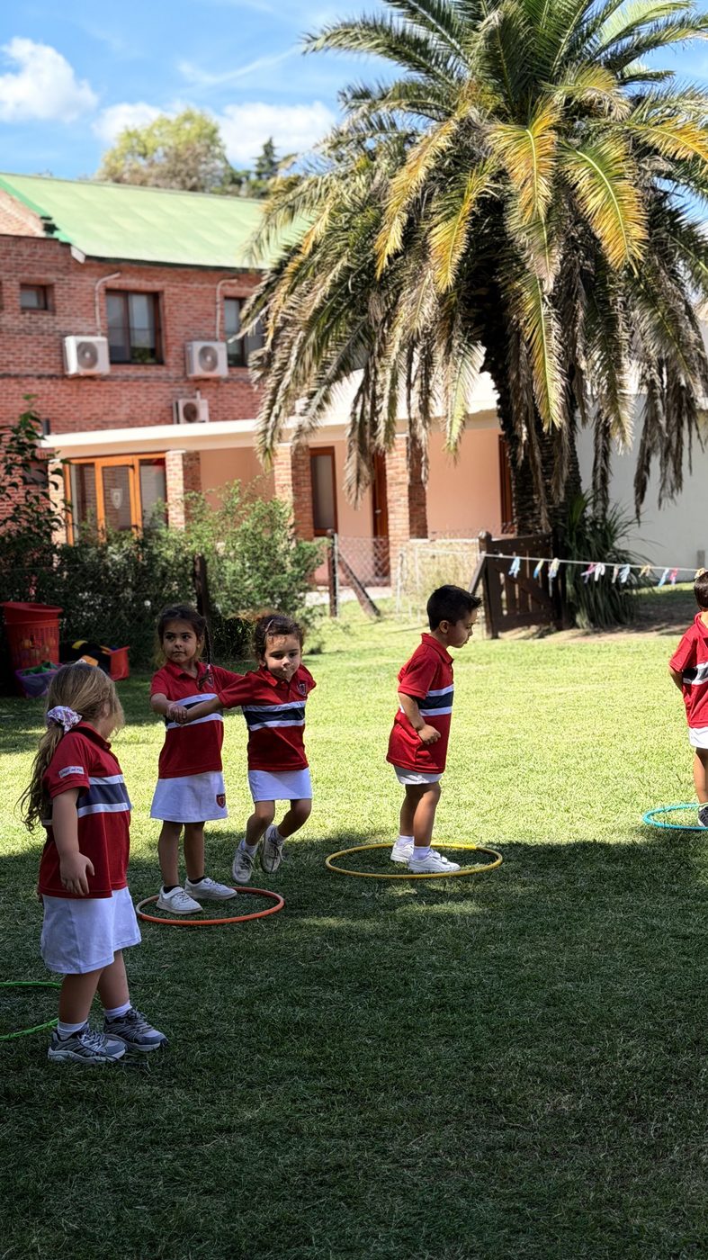 Alumnos de Kinder jugando con aros en el jardín del colegio